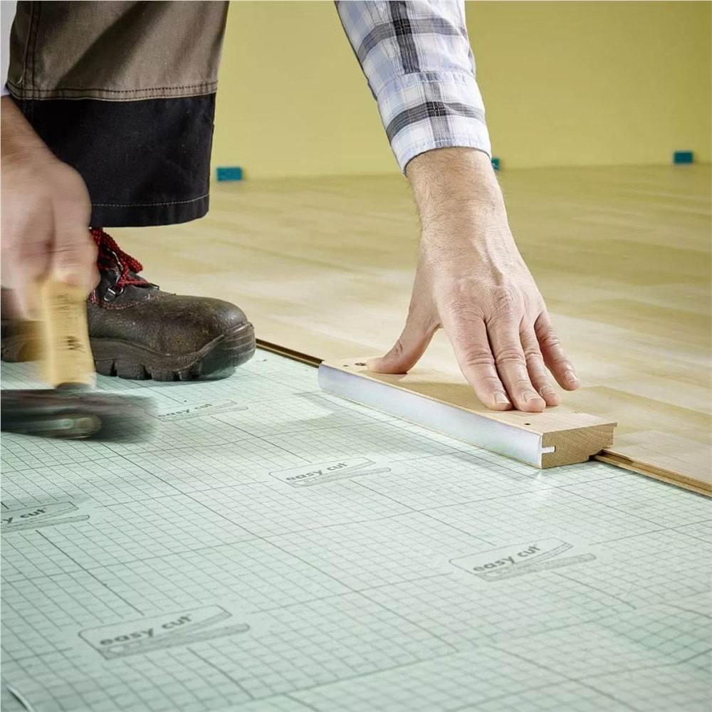 Person using tapping block to install laminate flooring over underlayment, demonstrating floor repair techniques.