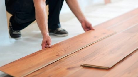 Person installing laminate flooring, showcasing professional floor installation services relevant to Star Flooring LLC, emphasizing quality and craftsmanship.